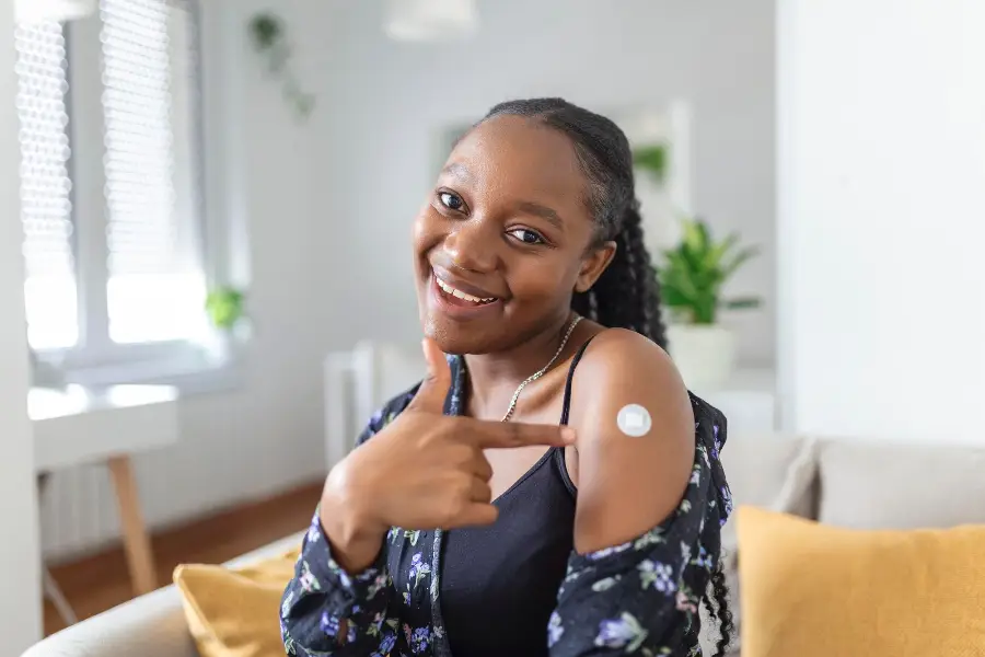 Portrait of a female smiling after getting a vaccine Woman holding down her shirt sleeve and showing her arm with bandage after receiving vaccination
